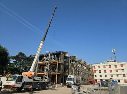 Grue de chantier en action devant la surélévation du site .