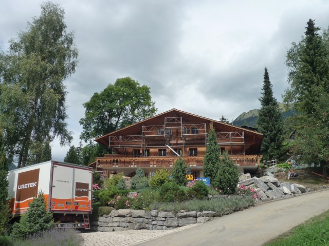 Photo d'un chalet suisse fissuré et affaissé et d'un camion d'intervention URETEK